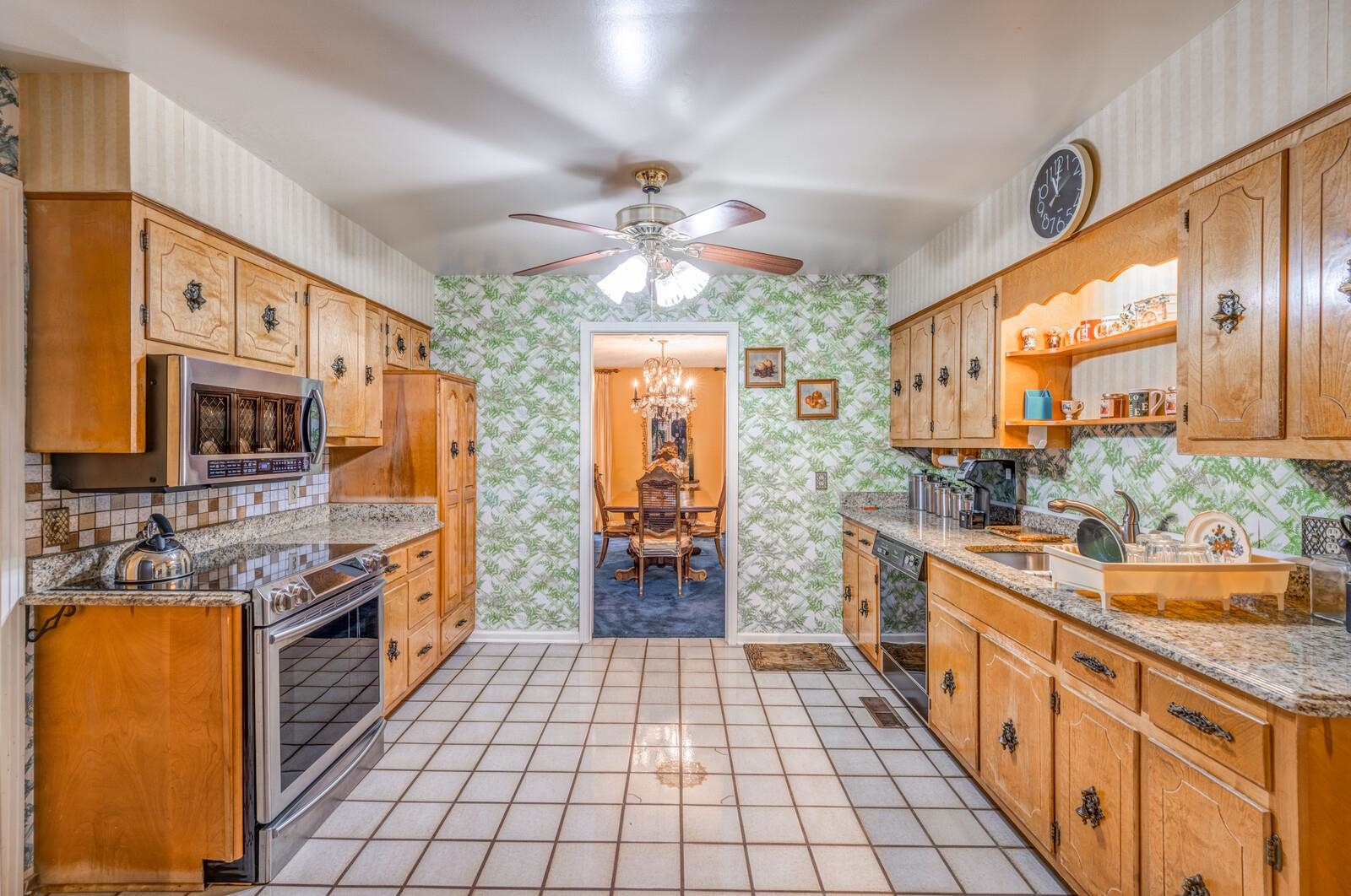 9715 Deadfall Road Brighton, TN 38011 - Photo 11 of 25 Kitchen with sink, light tile patterned floors, stainless steel appliances, light stone countertops, and ceiling fan with notable chandelier
