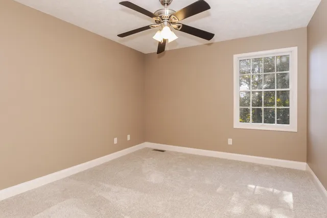 a view of an empty room and chandelier fan