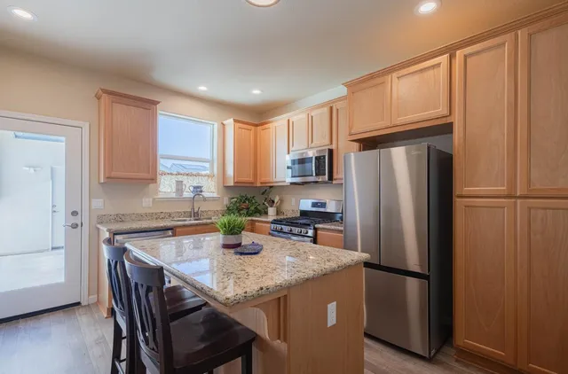 a kitchen with stainless steel appliances granite countertop a refrigerator a stove a microwave and cabinets