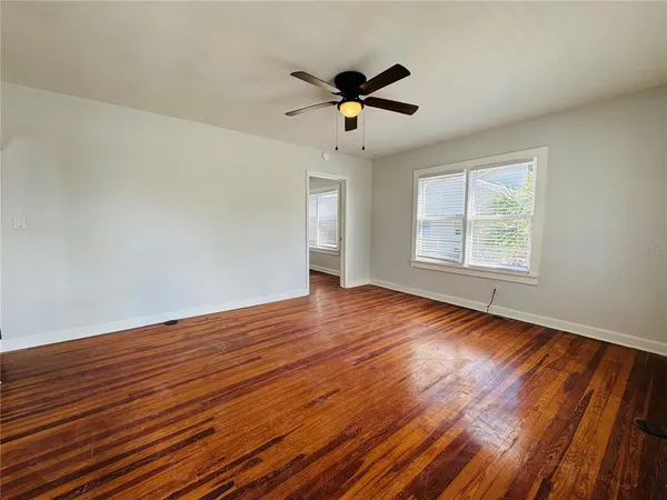 a view of an empty room with wooden floor and a window