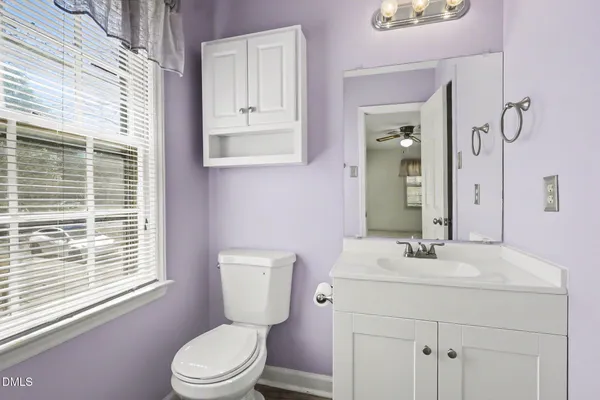 a bathroom with a toilet a sink a mirror a window and vanity