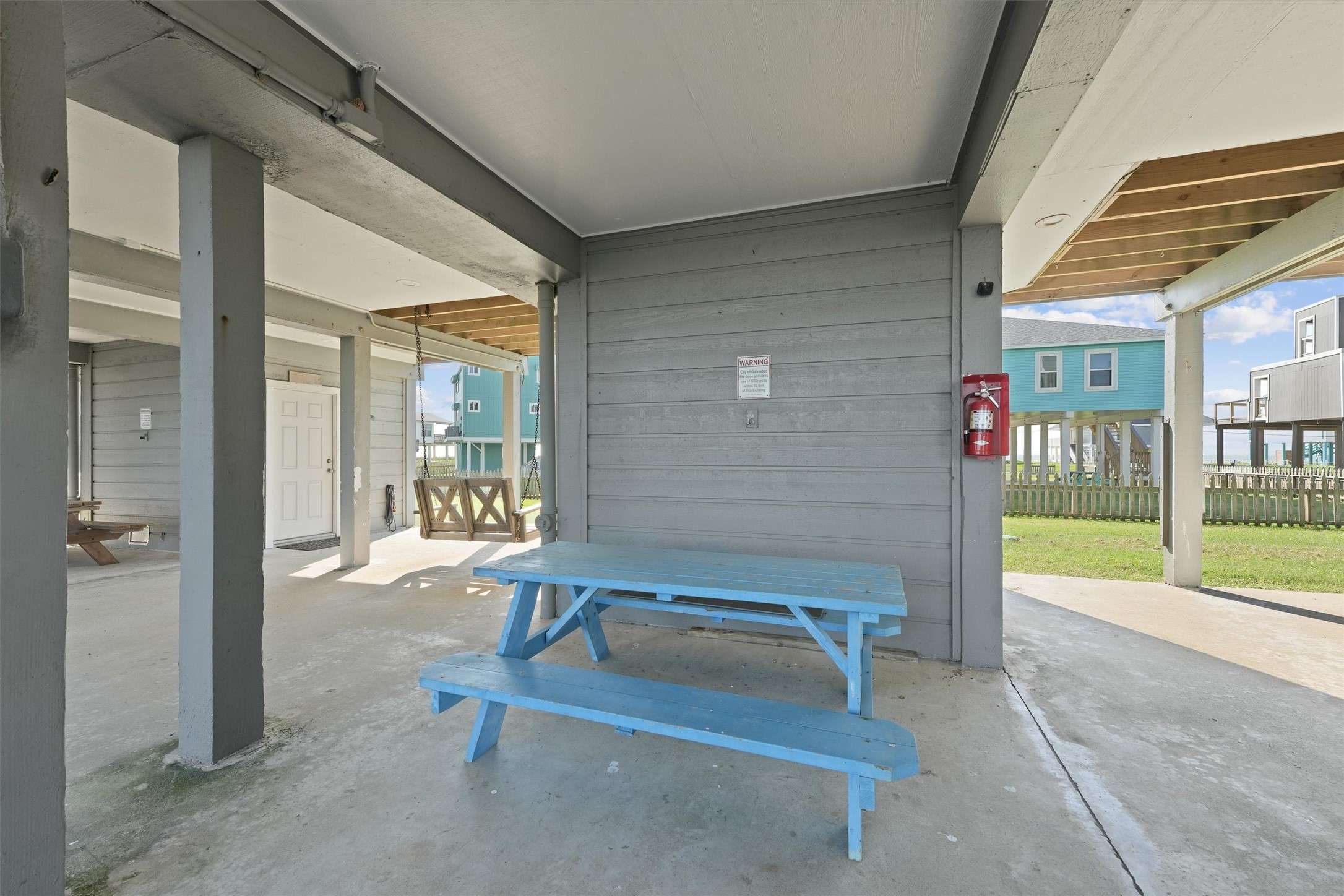 17607 Termini-San Luis Pass Road Galveston, TX 77554 - Photo 36 of 42 This covered area includes a bright blue picnic table, offering a great spot for casual outdoor meals. The covered patio provides additional shaded space, ideal for entertaining or storing beach essentials.