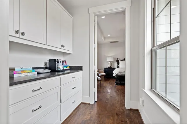 a kitchen with white cabinets and wooden floor