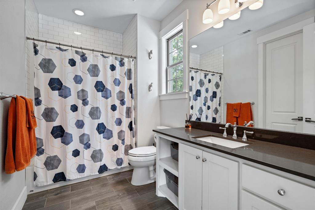 7102 Coronado Avenue Dallas, TX 75214 - Photo 17 of 30 a bathroom with a sink a toilet a mirror and shower curtain
