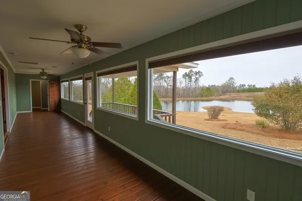 a view of a room with wooden floor fan and windows