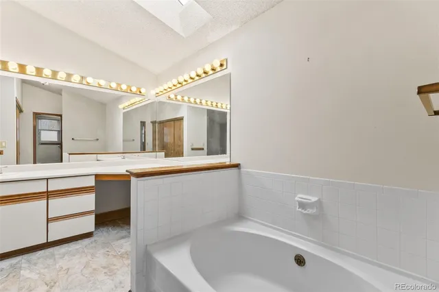 a spacious bathroom with a tub sink and mirror