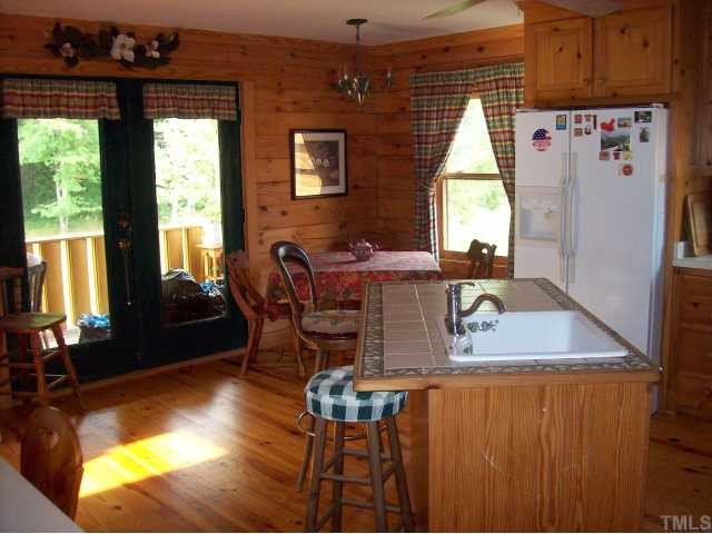 493 McGee Road Benson, NC 27504 - Photo 3 of 12 Bright kitchen and breakfast area with french doors leading to one of the two covered porches. Breakfast on the porch features bluebirds, humming birds and a gorgeous view of the back and woods. Tin chandelier is a Moravian style. Kitchen