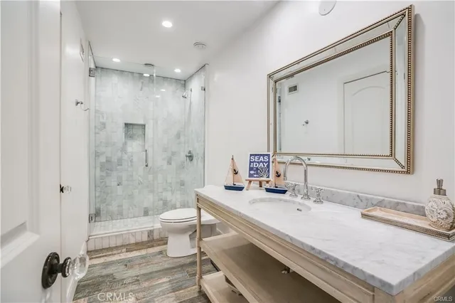 a bathroom with a granite countertop sink a toilet a mirror and shower