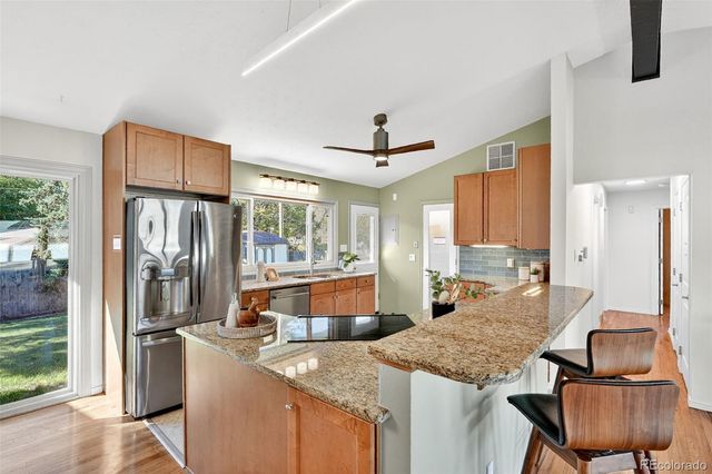 a kitchen with granite countertop kitchen island stainless steel appliances a sink and a refrigerator