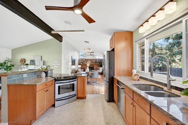 a kitchen with stainless steel appliances granite countertop a sink a stove and a refrigerator