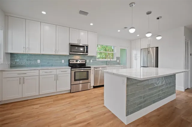a kitchen with kitchen island granite countertop white cabinets a sink and stainless steel appliances