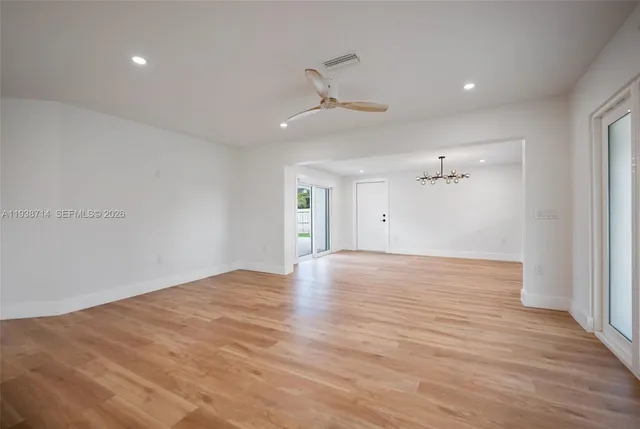 an empty room with wooden floor chandelier and windows