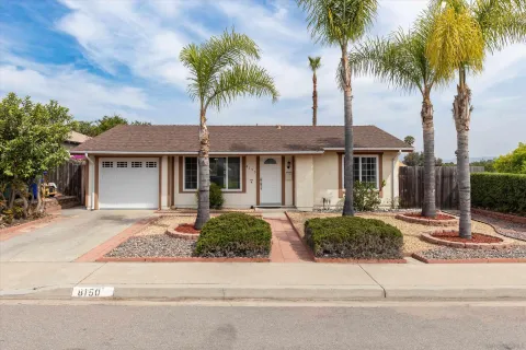 front view of a house with a yard and palm trees