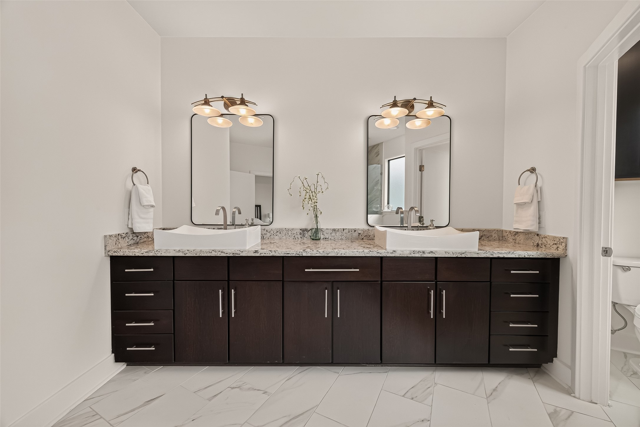 1767 Michigan Street Houston, TX 77006 - Photo 23 of 33 The primary bathroom features a modern double vanity with dark wood cabinets, granite countertops, and elegant vessel sinks. It includes large mirrors and stylish lighting, offering a clean and contemporary feel.