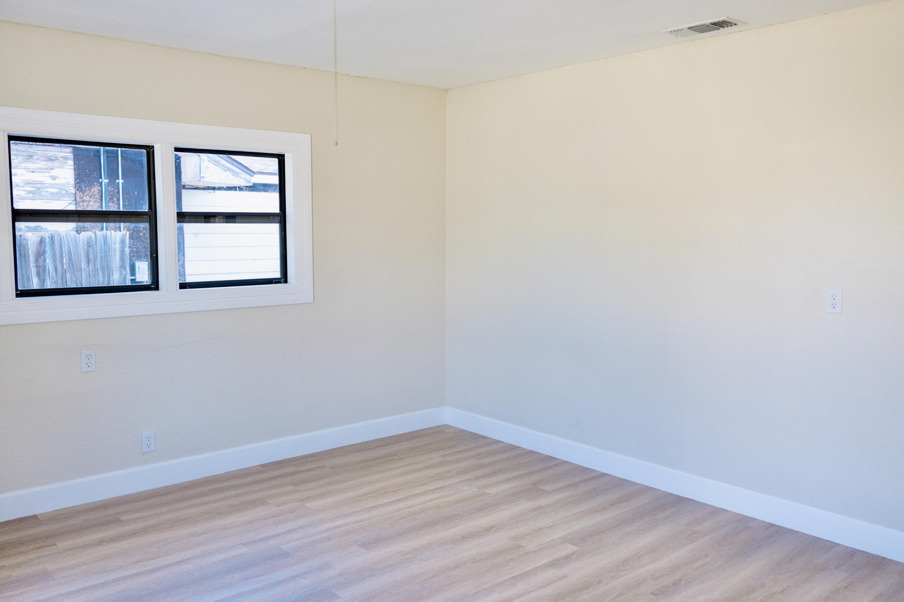 1410 West 8th Street Plainview, TX 79072 - Photo 14 of 24 a view of an empty room with wooden floor and a window