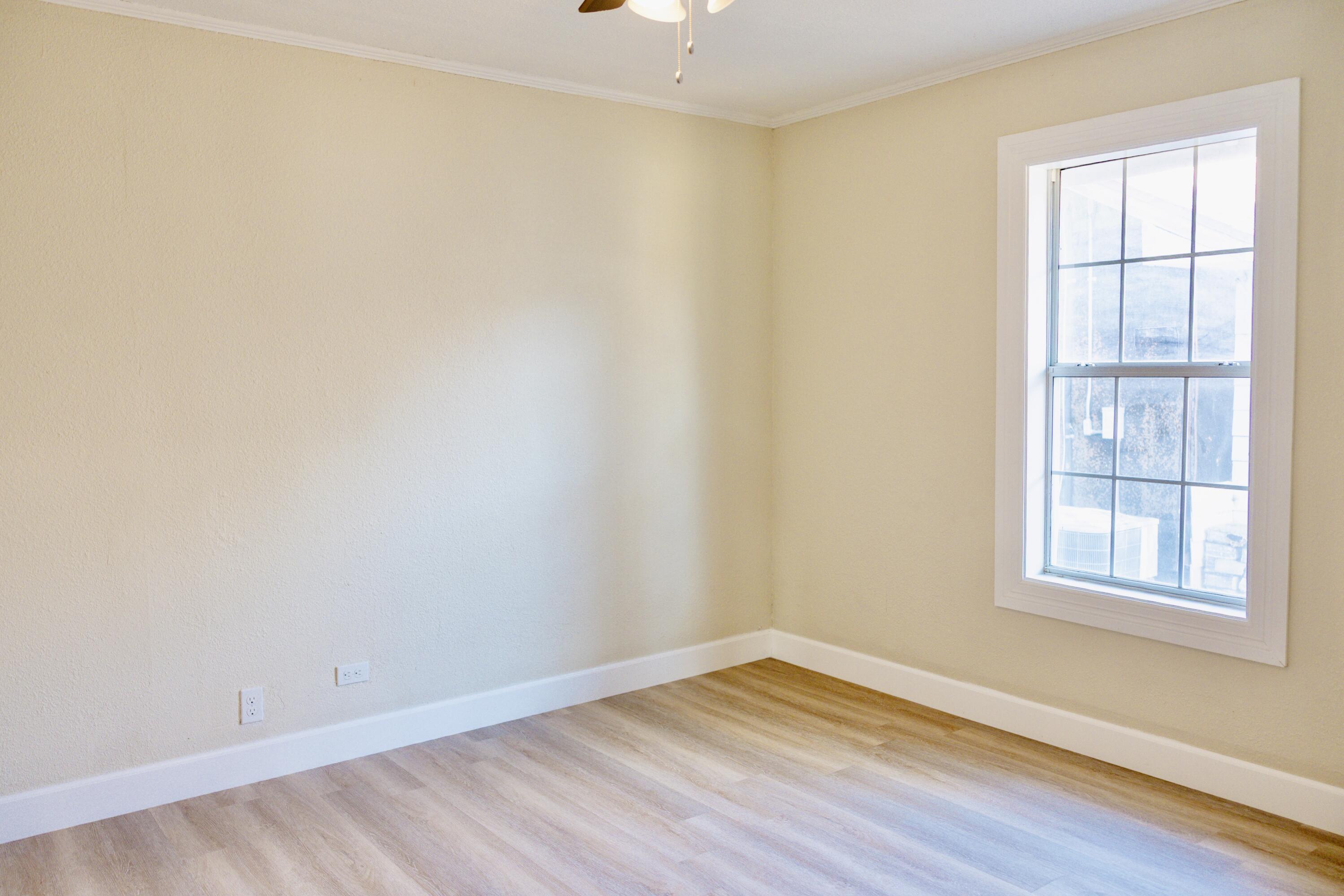 1410 West 8th Street Plainview, TX 79072 - Photo 20 of 24 an empty room with wooden floor and windows