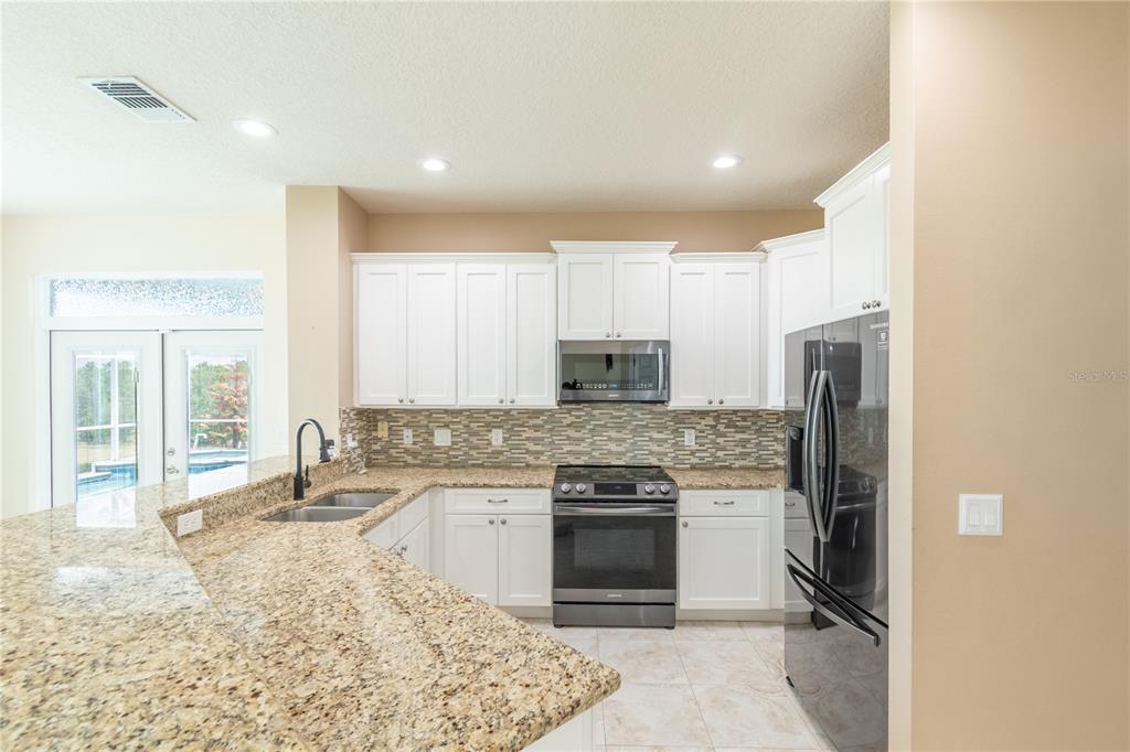 3862 Beacon Ridge Way Clermont, FL 34711 - Photo 27 of 56 a kitchen with stainless steel appliances granite countertop a stove a sink and a refrigerator