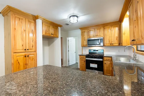 a kitchen with stainless steel appliances granite countertop a refrigerator stove and sink