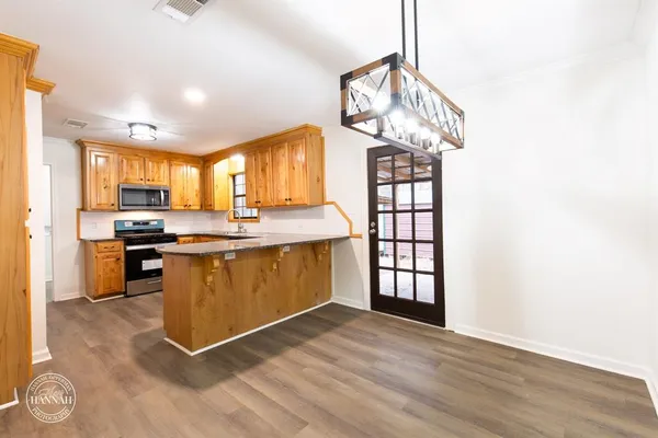 a kitchen with stainless steel appliances granite countertop a stove a sink dishwasher and a refrigerator with wooden floor