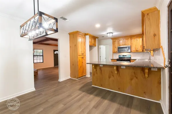 a kitchen with stainless steel appliances granite countertop a refrigerator a stove and a wooden floors