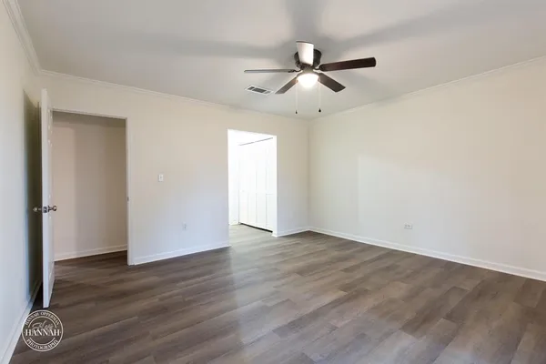 an empty room with wooden floor ceiling fan and windows