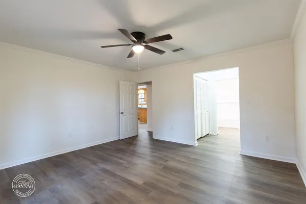 an empty room with wooden floor fan and windows
