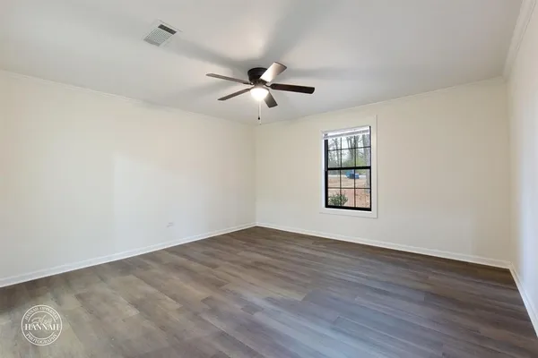 an empty room with wooden floor ceiling fan and windows