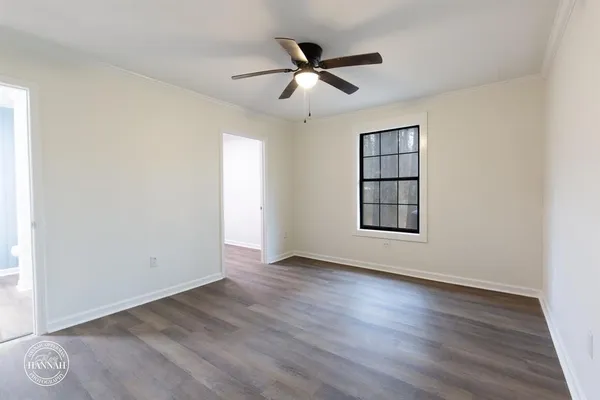 an empty room with wooden floor ceiling fan and windows