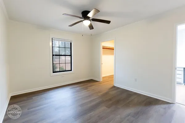 an empty room with wooden floor chandelier fan and windows