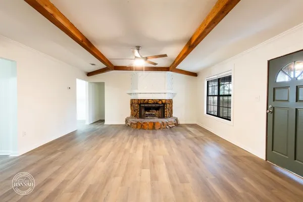 a view of empty room with fireplace and wooden floor