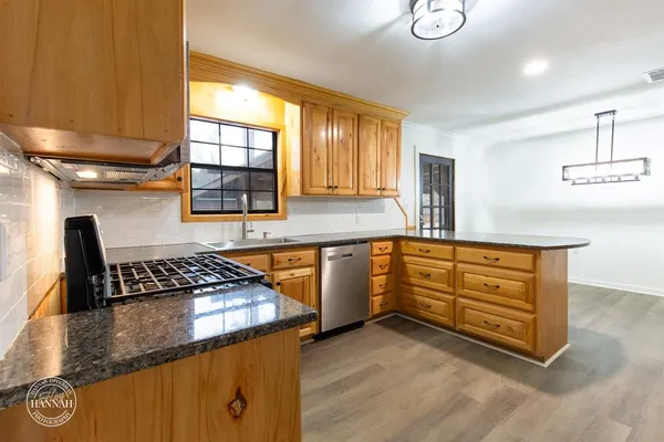 a kitchen with granite countertop a sink a stove counter space and cabinets