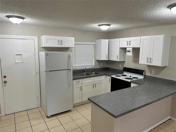 a kitchen with granite countertop a refrigerator sink and stove