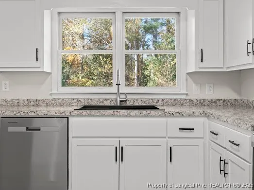 a kitchen with granite countertop white cabinets and a window