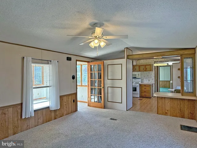 wooden floor in an empty room with a window and a kitchen