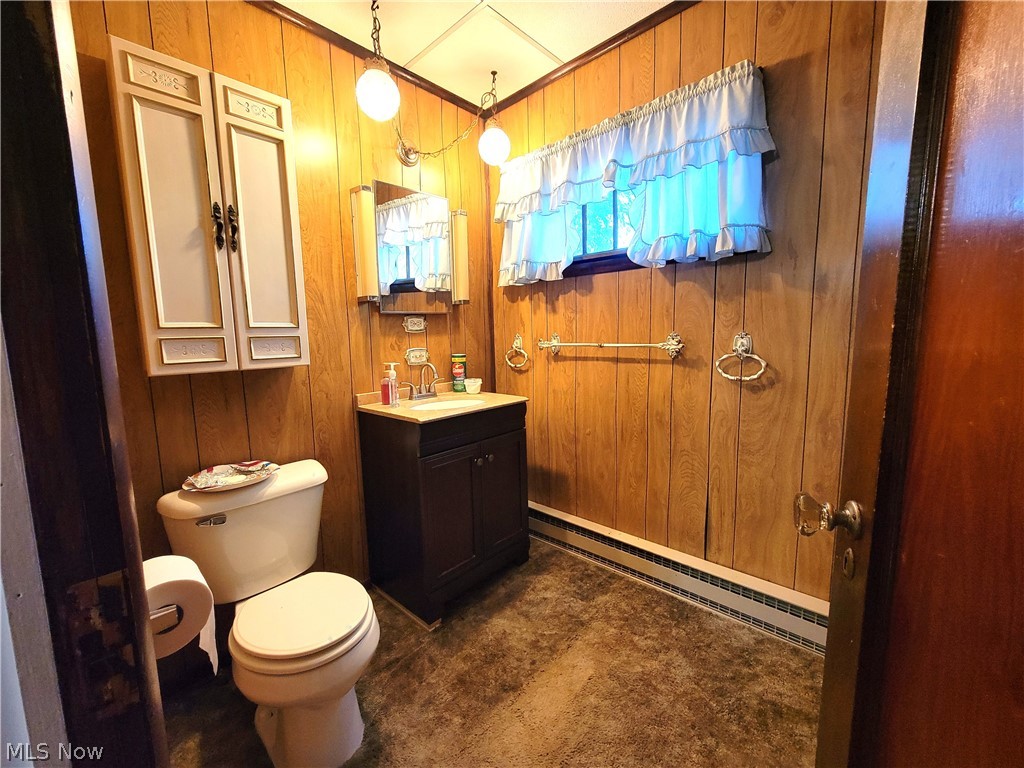 50658 Marietta Road Cumberland, OH 43732 - Photo 10 of 14 Bathroom with a baseboard radiator, vanity, wooden walls, and toilet