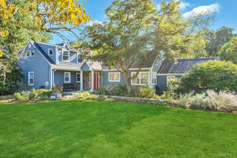 a front view of a house with a garden and trees