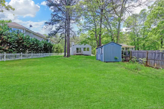 a view of a backyard with large trees and wooden fence