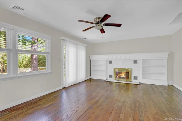 a view of empty room with wooden floor and window