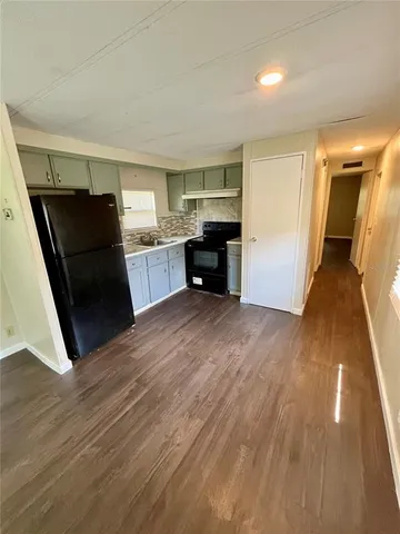 a view of a kitchen with refrigerator and wooden floor
