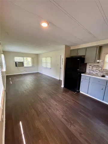a living room with hard wood floors and a kitchen