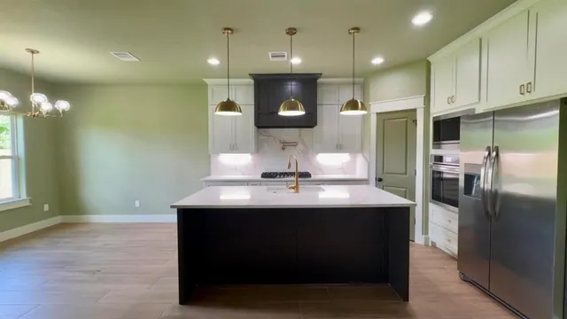 a kitchen with kitchen island a sink stainless steel appliances and cabinets