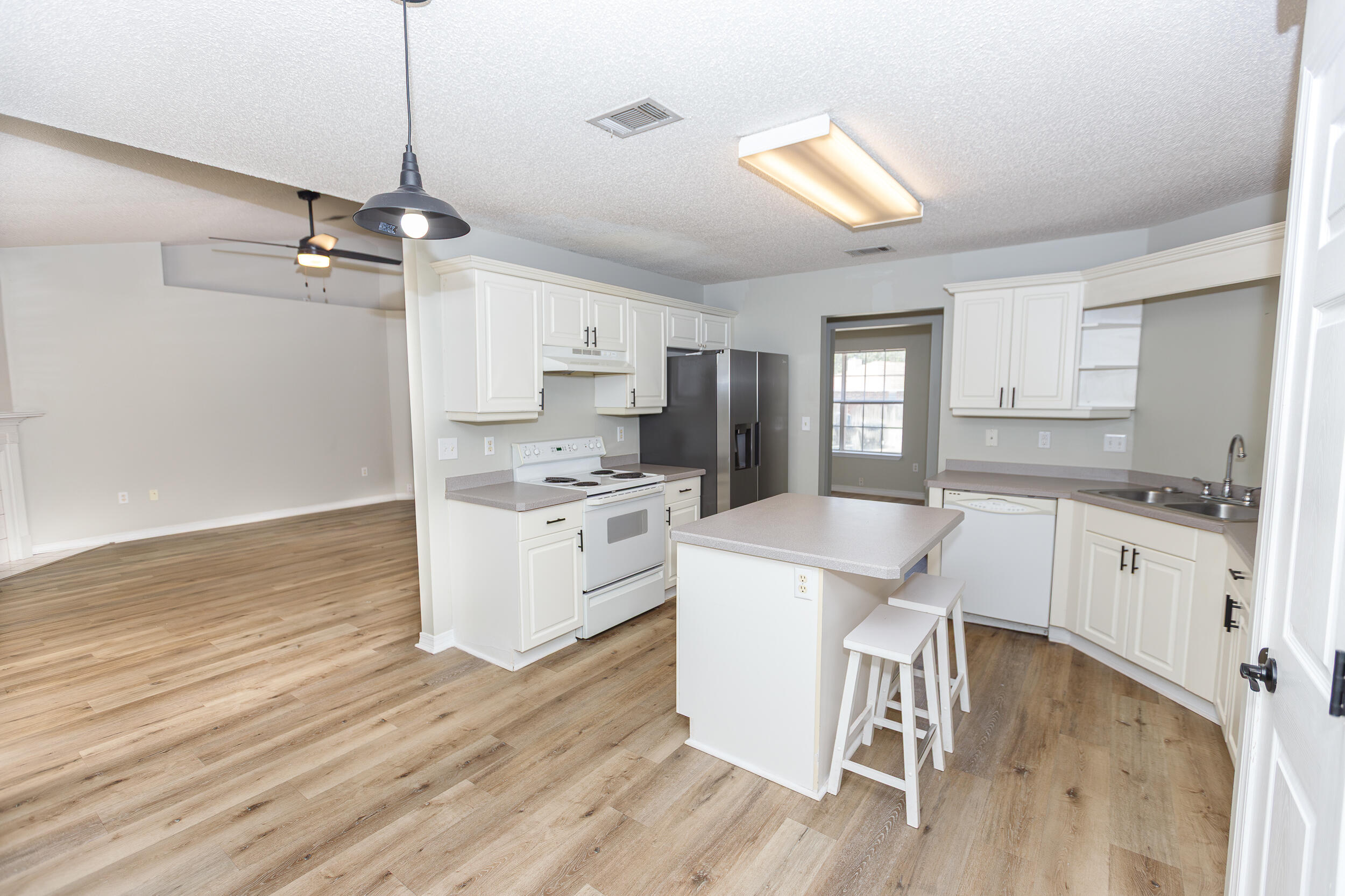 1305 Jefferyscot Court Crestview, FL 32536 - Photo 8 of 20 a kitchen with a table chairs refrigerator and white cabinets