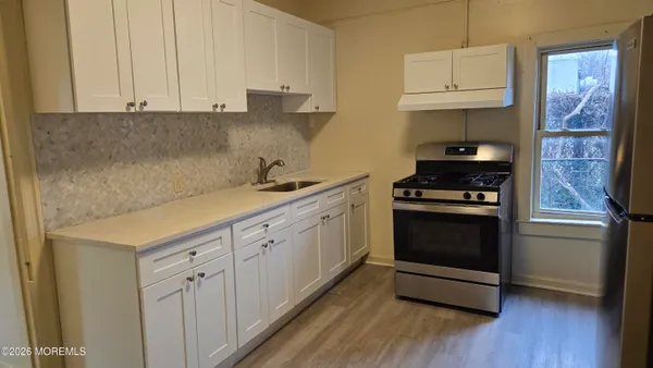 a kitchen with stainless steel appliances white cabinets and a stove top oven