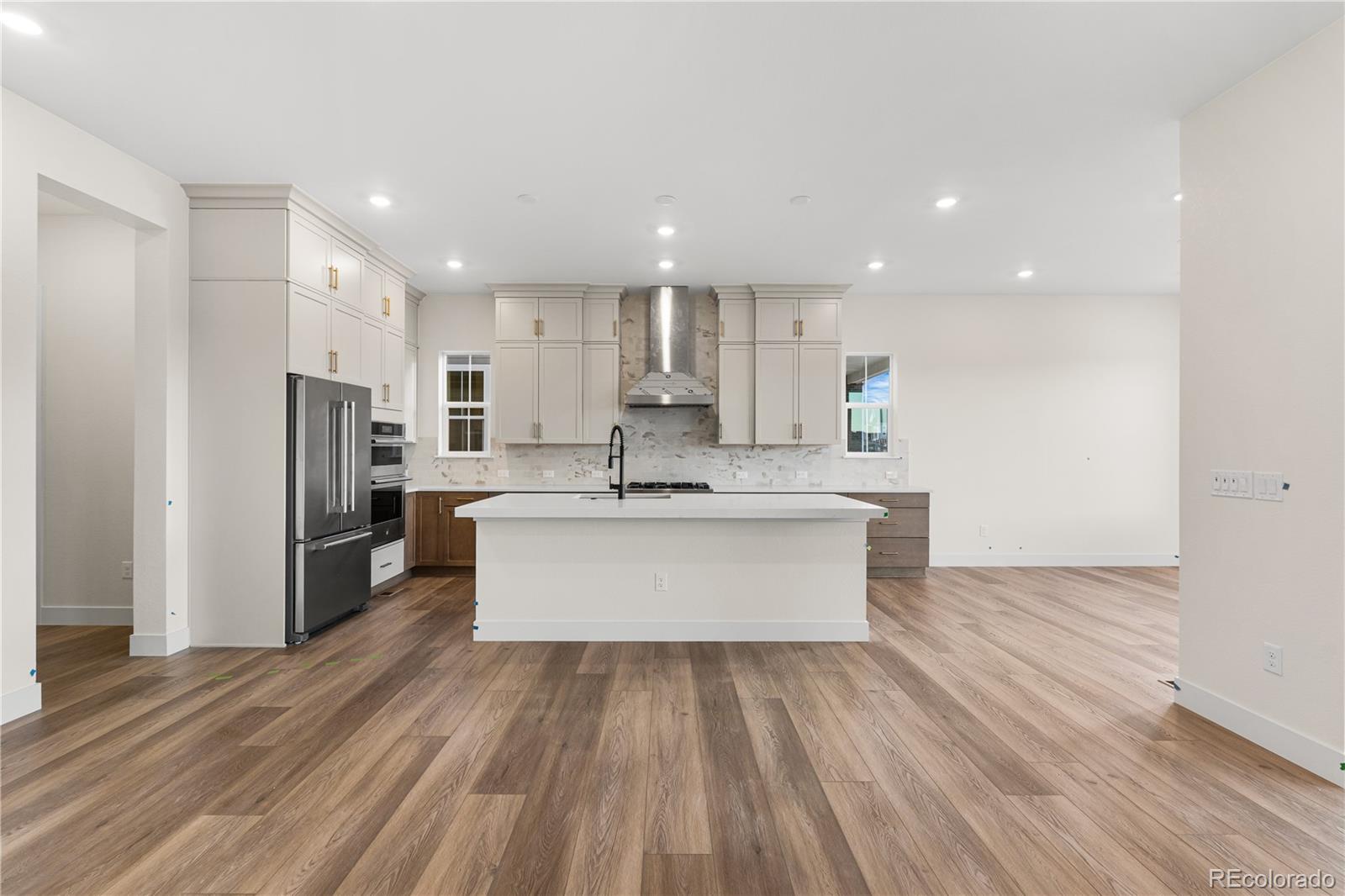 6749 Fawn Path Lane Castle Pines, CO 80108 - Photo 14 of 33 a large kitchen with kitchen island a sink dishwasher a refrigerator and white cabinets with wooden floor