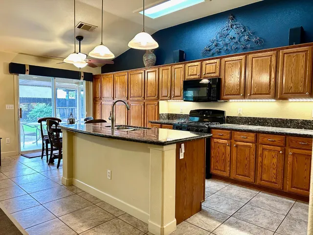 a kitchen with granite countertop a stove a sink a counter top space and cabinets
