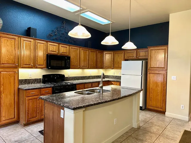 a kitchen with stainless steel appliances granite countertop a sink a microwave oven and a refrigerator