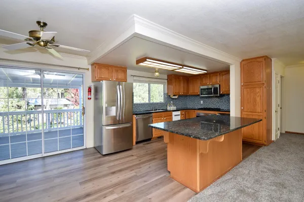 a kitchen with stainless steel appliances granite countertop a refrigerator a stove and a sink
