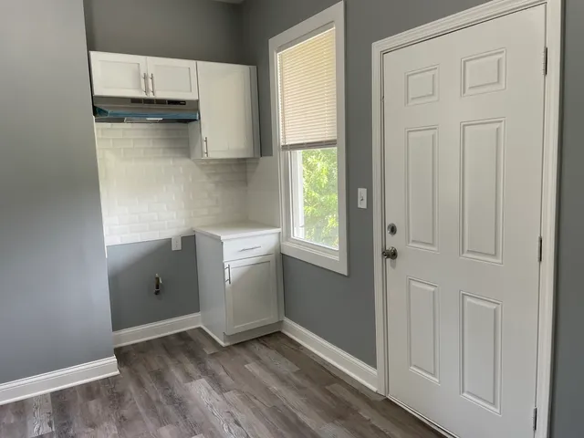 a view of a kitchen with white cabinets and wooden floor