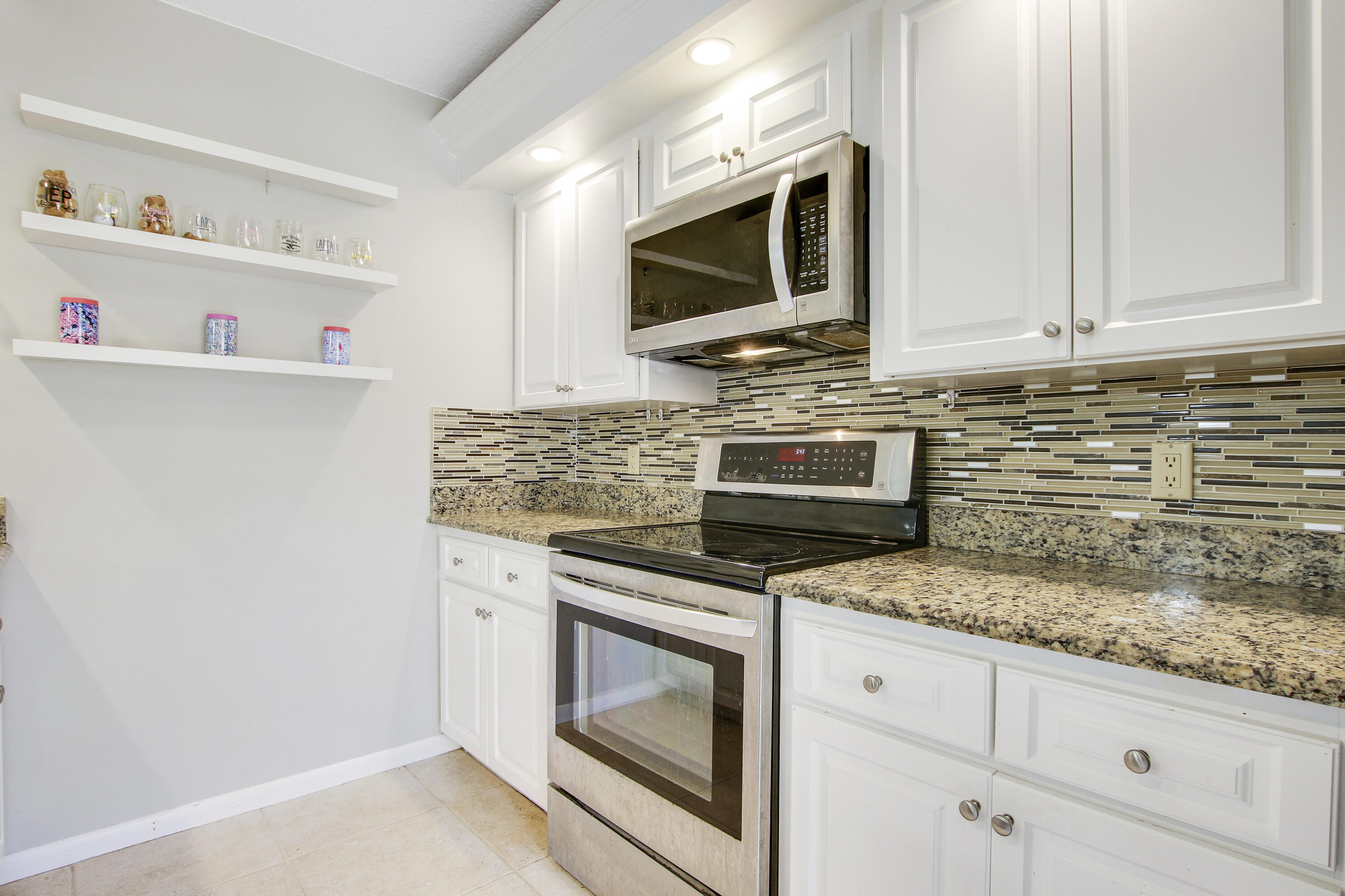 1205 12th Court Jupiter, FL 33477 - Photo 5 of 13 a kitchen with granite countertop white cabinets stainless steel appliances and a sink