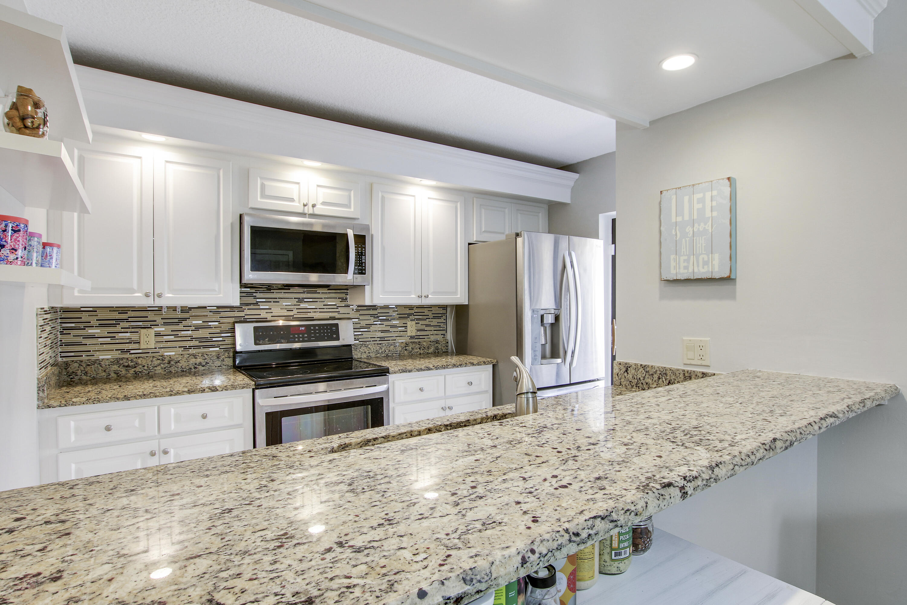 1205 12th Court Jupiter, FL 33477 - Photo 6 of 13 a large kitchen with granite countertop a stove a sink and a microwave